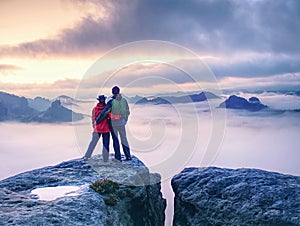 Couple on mountain looking over heavy mist to  horizon