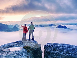 Couple on mountain looking over heavy mist to  horizon