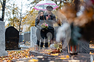 Couple mourning a deceased loved one on cemetery in fall