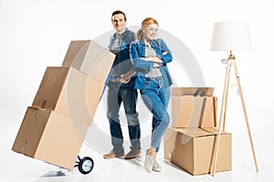 Couple moving cardboard boxes on hand cart