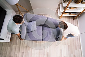 Couple Moving And Carrying Sofa Furniture