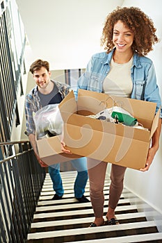 Couple Moving Into New Home Carrying Box Upstairs