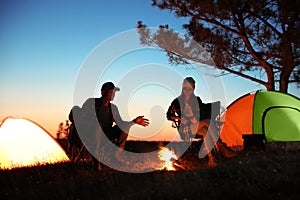 Couple near bonfire in evening. Camping season photo