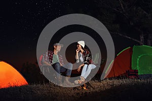 Couple near bonfire at night. Camping season