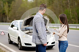 Couple near broken car on a roadside