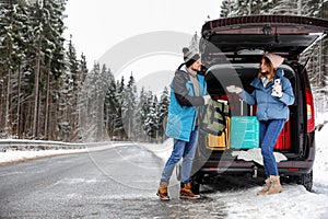 Couple near open car trunk full of luggage on road, space for text.