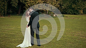 Couple of newlyweds embrace. Groom touches hair with his lips bride closes eyes.