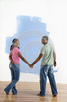 Couple next to half-painted wall.