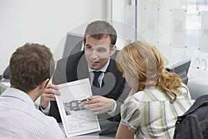 Couple Observing Brochure With Real Estate Agent