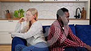 Couple offended at each other sit on couch back to back, relationship problems