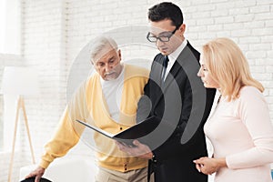 A couple of old people at a reception with a realtor. They stand next to a realtor and shockingly read the form.