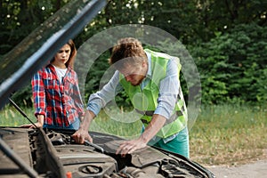 Couple at the opened hood on road, car breakdown