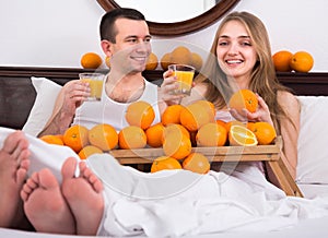 Couple with orange juice in bed.