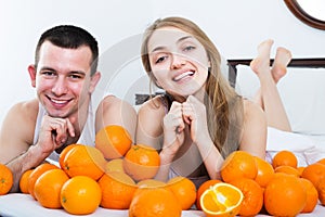 Couple with oranges in bed