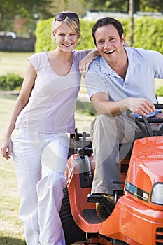 Couple outdoors with lawnmower smiling