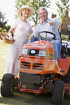 Couple outdoors with tools and lawnmower pointing