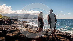 Couple overlooks the ocean off a rocky Kauai coast