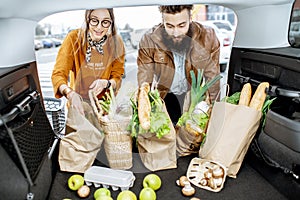 Couple packing shopping bags into the car trunk