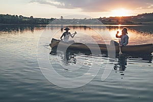 Couple paddling canoe on the sunset lake