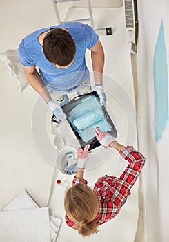 Couple with paint roller painting wall at home