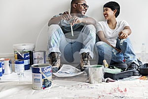 Couple painting house wall taking break