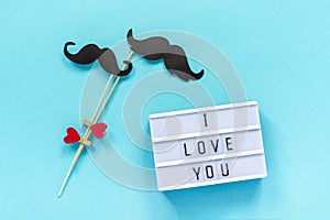 Couple paper mustache props and light box with text I love you on blue background. Concept Homosexuality gay love. National Day