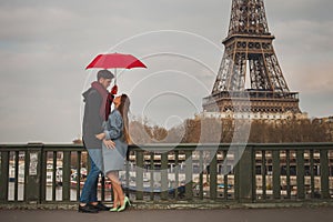 Couple in Paris near Eiffel tower in autumn, dating, man and woman kissing under umbrella