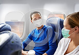 Couple of passengers in masks travelling by plane