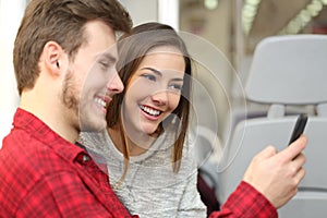 Couple of passengers sharing a smart phone inside a train