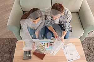 Couple with pay bills, calculator and money counting expenses indoors. Money savings concept