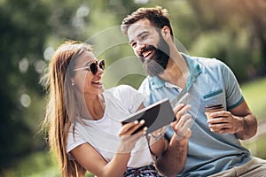 Couple paying on line with credit card and digital tablet outdoor