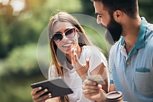 Couple paying on line with credit card and digital tablet outdoor