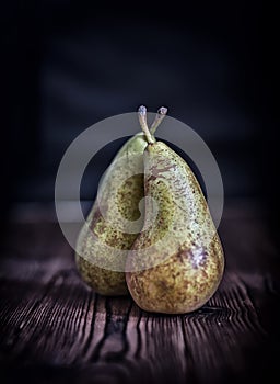 Couple pears on old rustic wooden table background, dark toned s