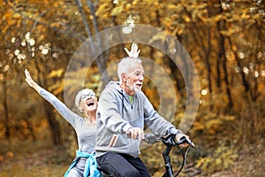 Couple of pensioners driving bike in park