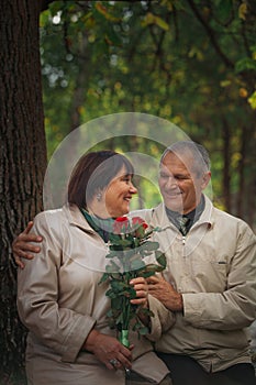 A couple of pensioners sits in an autumn park on a bench