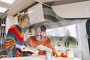 Couple of people enjoy leisure indoor in a camper camping car. Adult man and woman smile and have fun during travel vacation or