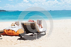 Couple of people reading while sunbathing on the beach