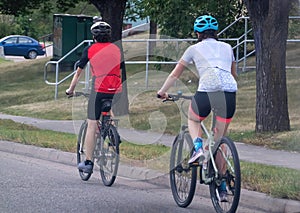 A couple of people riding their bicycles on a busy street during summer. Concept: Cycling