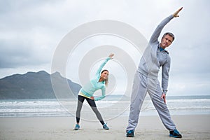 Couple performing stretching exercise on beach