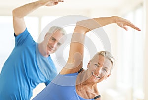 Couple Performing Stretching Exercise At Home