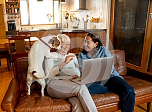 Couple with pet dog chatting online or video calling friend enjoying life at home together