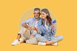 Couple with phone and credit card, engaged in online shopping