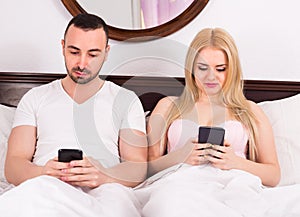 Couple with phones in bed