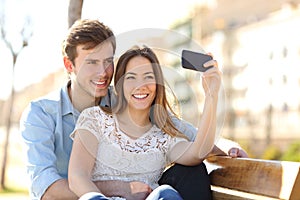 Couple photographing a selfie with a smart phone in a park