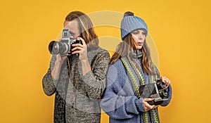 Couple of photojournalists hold photo cameras taking photograph yellow background, paparazzi