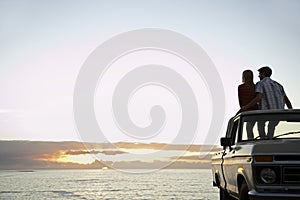 Couple On Pick-Up Truck Parked In Front Of Ocean