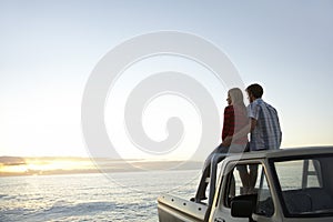 Couple On Pick-Up Truck Parked In Front Of Ocean