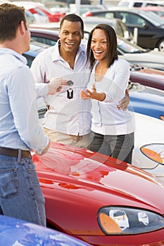 Couple picking up new car from salesman