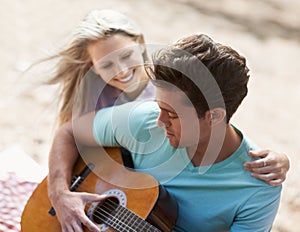 Couple, picnic and playing guitar for romance, love or song in outdoor bonding, fun or relaxing together in nature. Man