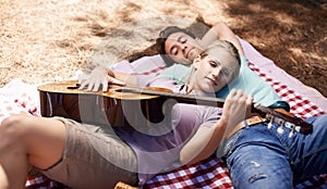 Couple, picnic and playing guitar for romance, music or love in outdoor bonding, fun or relaxing together in nature